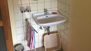 A small bathroom with a white sink, mirror, and a red rug. - Gästehaus Erna Meier (Bayerisch Eisenstein)