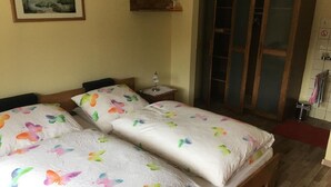 A room with two beds, each with butterfly-patterned bedding, a small bedside table with a lamp, and a painting on the wall. - Gästehaus Erna Meier (Bayerisch Eisenstein)