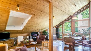 A spacious loft with wooden floors, a large skylight, and a view of greenery outside. - Holiday Apartment “Rose Garden” near Lake Constance with Wi-Fi & Balcony (Heiligenberg)