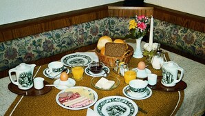 A breakfast table set with plates, bowls, cups, and a basket of bread.