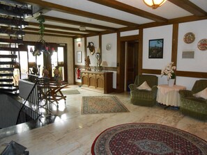 A spacious living area with a dining table, two armchairs, a coffee table, and a patterned rug. - Pension Sonnenblick (Winterberg)