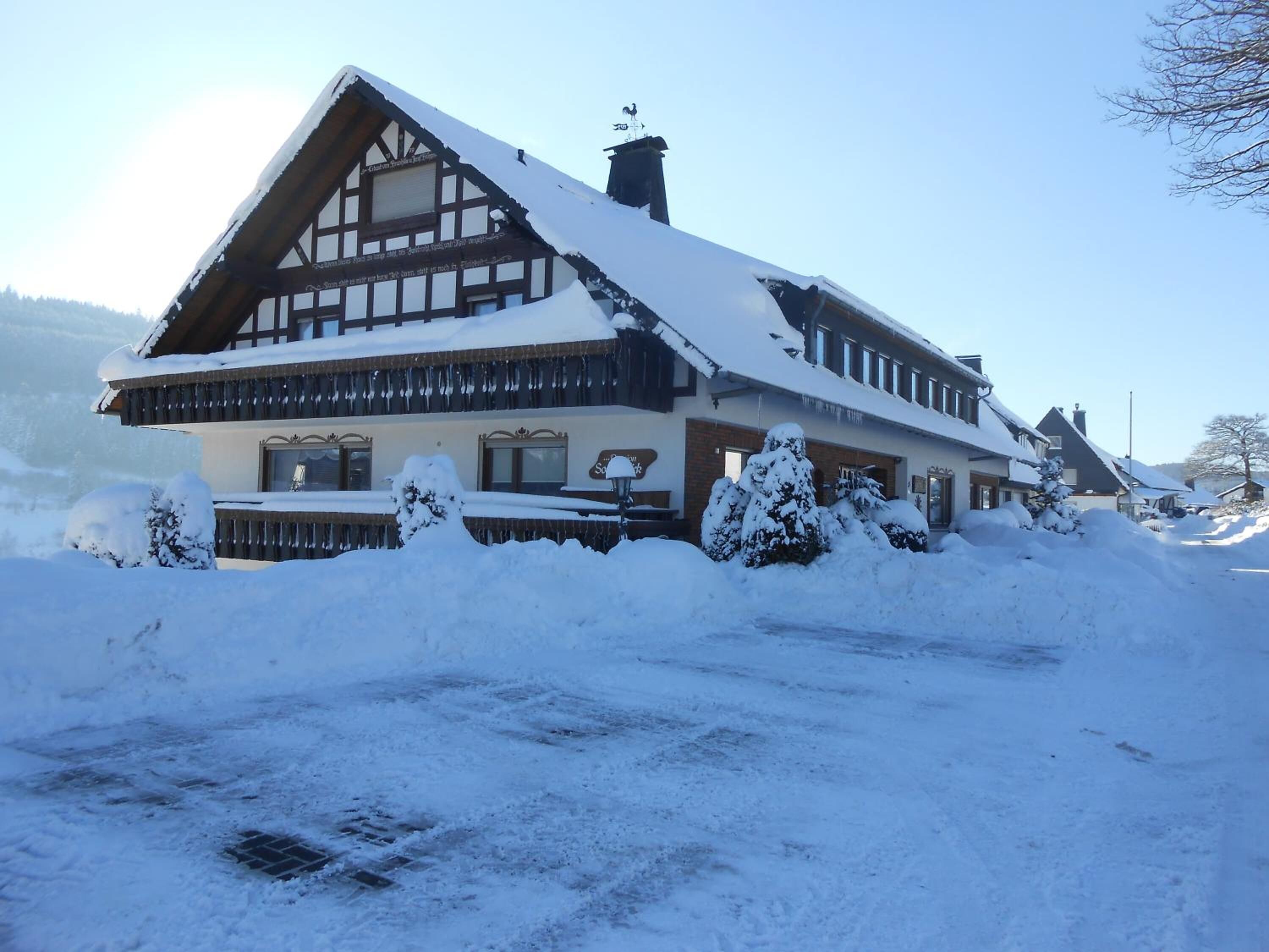 A traditional chalet-style building with a steeply pitched roof, wooden exterior, and snow-covered surroundings.