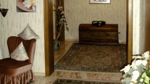 Una habitación con un banco de madera, una silla con cojines, un tapete estampado y un cuadro en la pared.