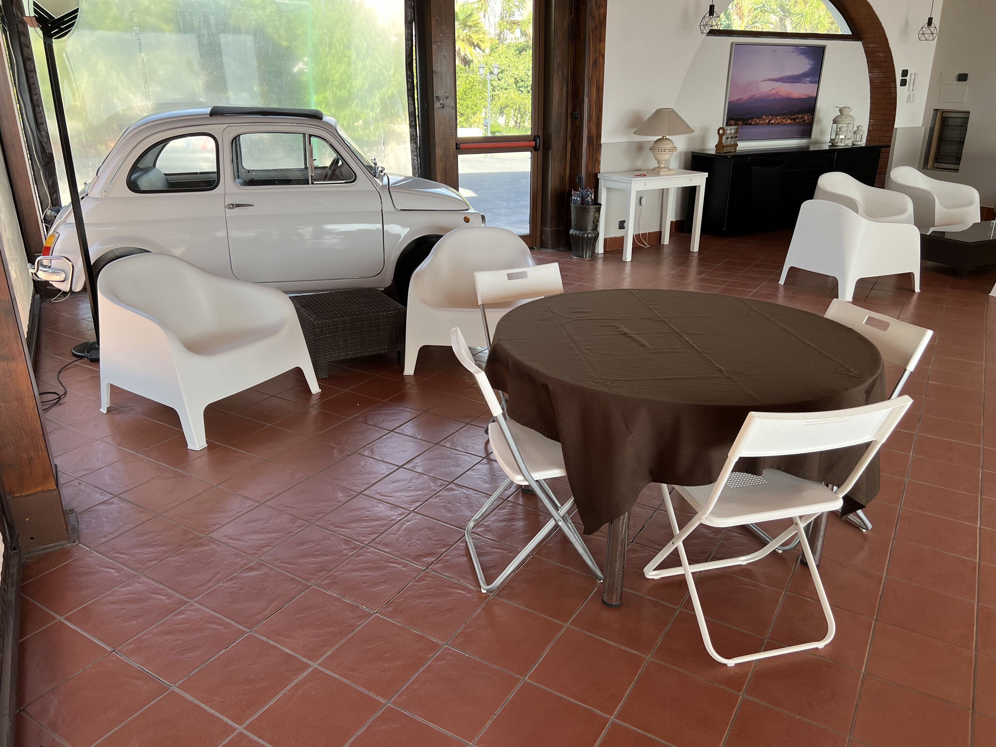 Ein Zimmer mit Esstisch, weißen Stühlen, einem Fernseher und einem Auto.