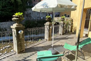 An outdoor seating area with a table and chairs, a white umbrella, and decorative planters.