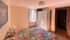 A bedroom with a bed, a radiator, a window, and a door. - Bridge Apartment Argegno (Argegno)