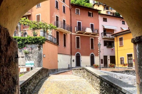 A courtyard with stone walls, a stone floor, and buildings with balconies and windows.