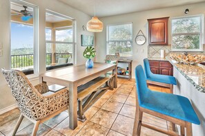 A kitchen with a dining area, a blue vase with flowers, and a view of the outdoors. - Scenic Terrace | Private Pool, Hot Tub, Gameroom (Canyon Lake)
