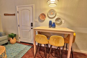 Een eetgedeelte met een houten tafel, twee gele stoelen en decoratieve borden aan de muur.