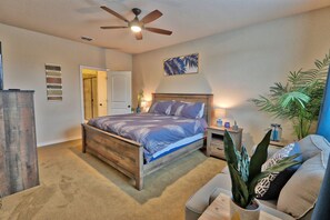 A bedroom with a bed, a ceiling fan, a nightstand, a potted plant, and a door. - Scenic Terrace | Private Pool, Hot Tub, Gameroom (Canyon Lake)