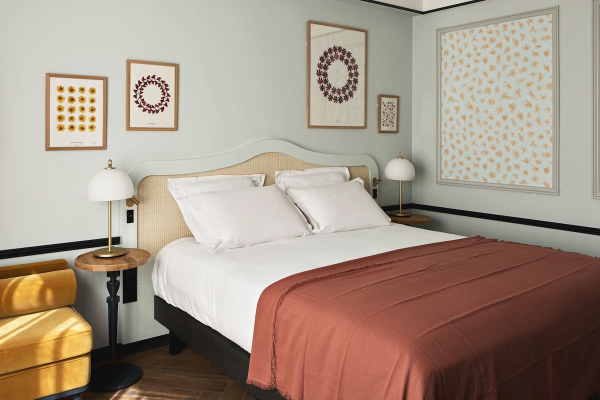 A neatly arranged bedroom with a bed, two bedside tables, a lamp, and a chair.