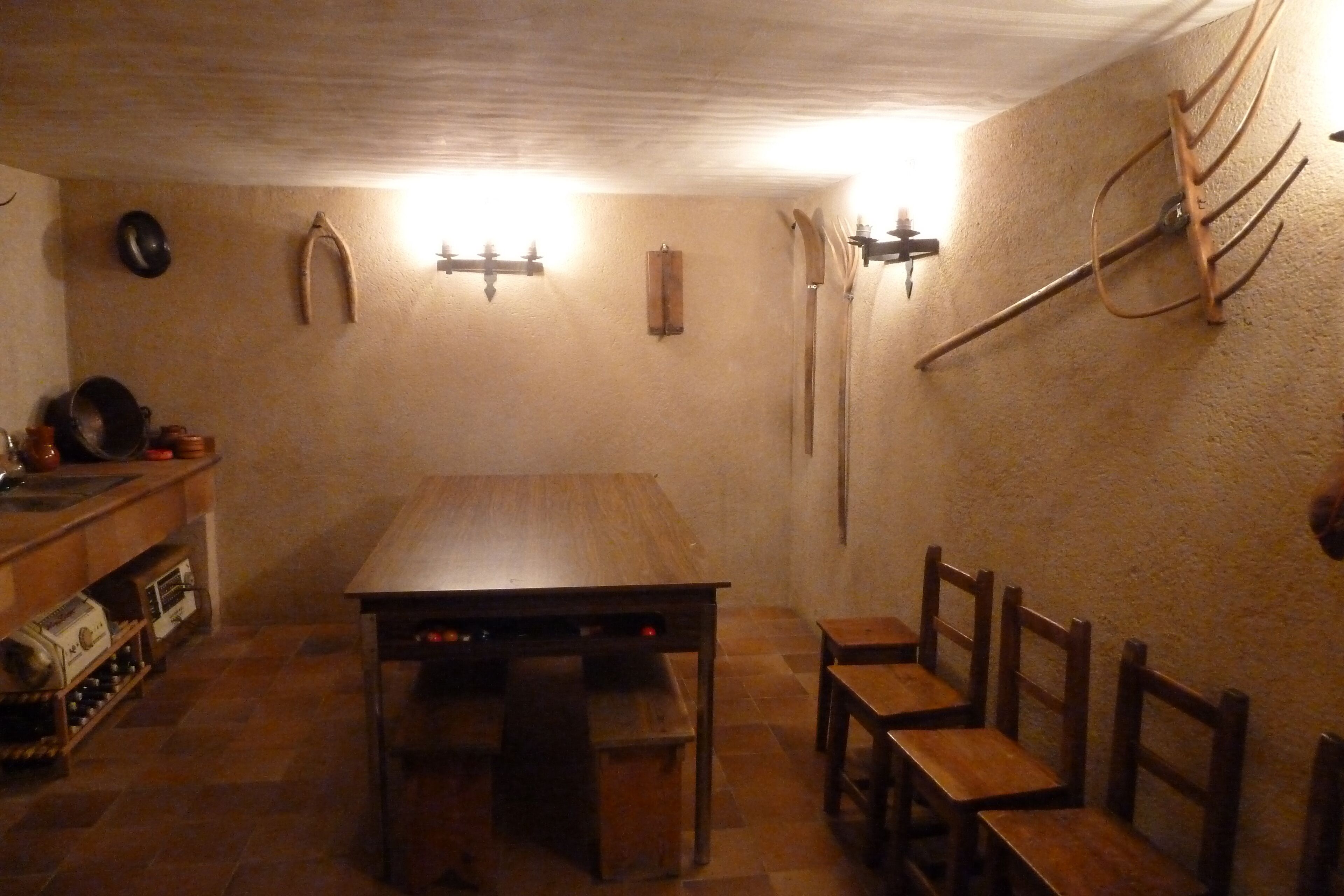 A dining area with a wooden table and benches, a wine rack, and a wall-mounted rack with hooks.