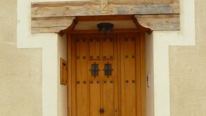 Eine Holztür mit der Zahl 2 darüber, eingebettet in einen schlichten Baustil und mit einer kleinen Stufe, die zum Eingang führt.