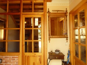 Une pièce avec des fenêtres à cadre en bois, un mur en briques et une petite table sur laquelle se trouvent un objet décoratif et un parapluie.