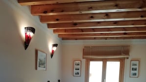 Ein Zimmer mit zwei Betten, Holzbalkendecke, einem Fenster mit Jalousien und Wandleuchten.