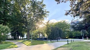 Un parc avec un chemin pavé, des arbres et une pelouse.
