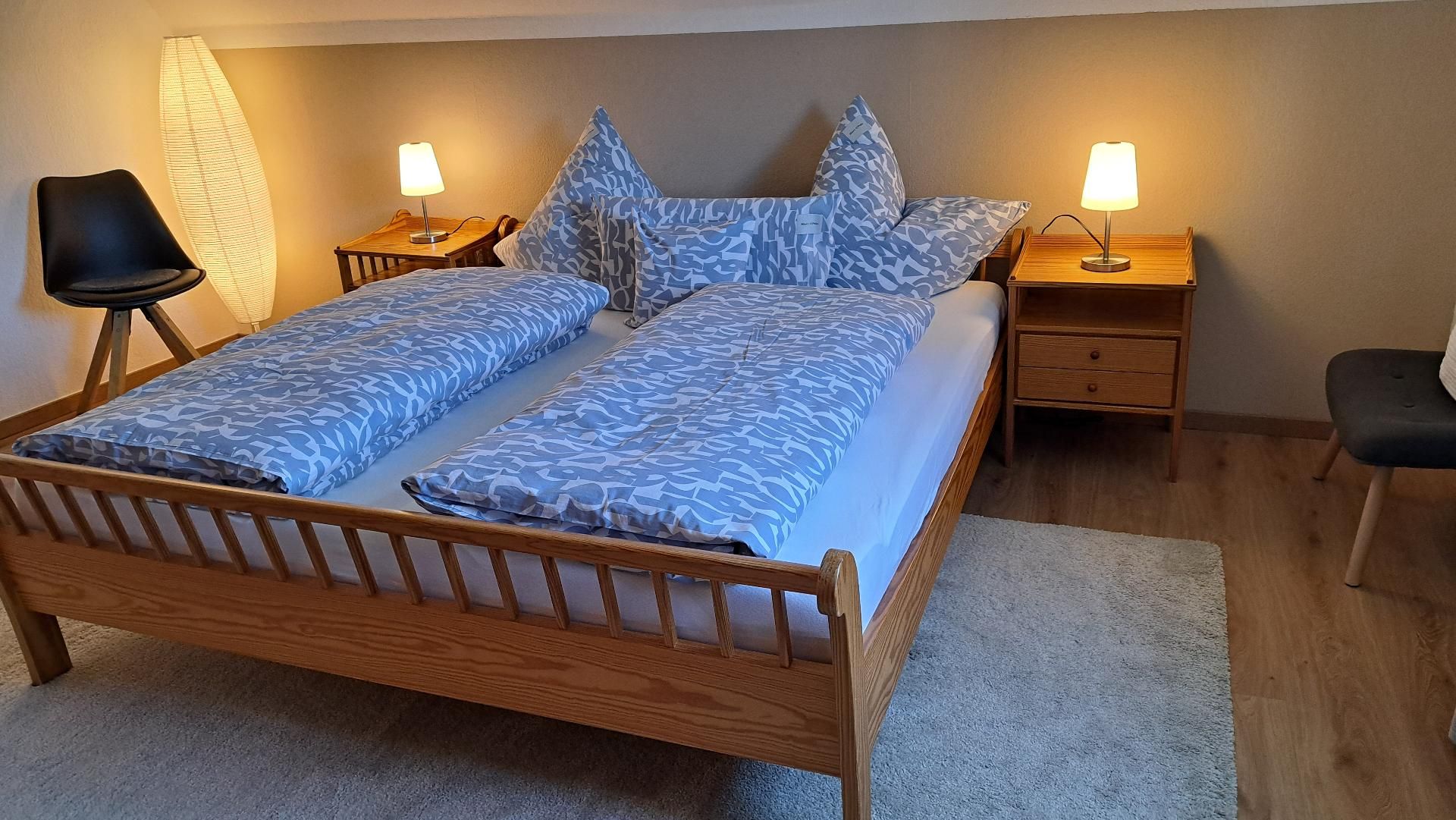 Un dormitorio con una cama de madera, mesitas de noche a juego y una silla.