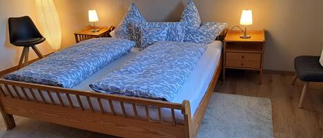 Un dormitorio con una cama de madera, mesitas de noche a juego y una silla.