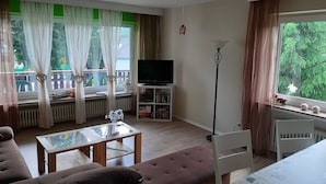 Un salon avec un canapé, une table basse en verre, un téléviseur et une bibliothèque.