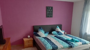 Une chambre à coucher comprenant un lit, une table de chevet, une commode et un tableau décoratif mural.