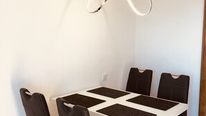 A dining area with a white table, black chairs, and a modern pendant light. - Ferienwohnung Frohwein (Winterberg)