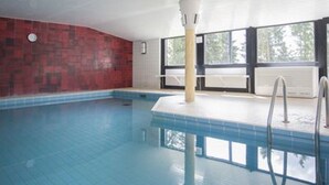 An indoor swimming pool with a red tiled wall, a white ceiling, and large windows. - Ferienwohnung Frohwein (Winterberg)