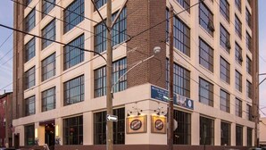 A multi-story building with a corner entrance, large windows, and a sign for 'Brand New Apparel'. - Sosuite | Studio w W/D, Gym, On-Site Restaurant (Philadelphia)