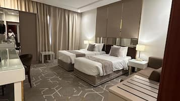 Une chambre d’hôtel avec un grand lit, deux tables de chevet, un bureau et une chaise.
