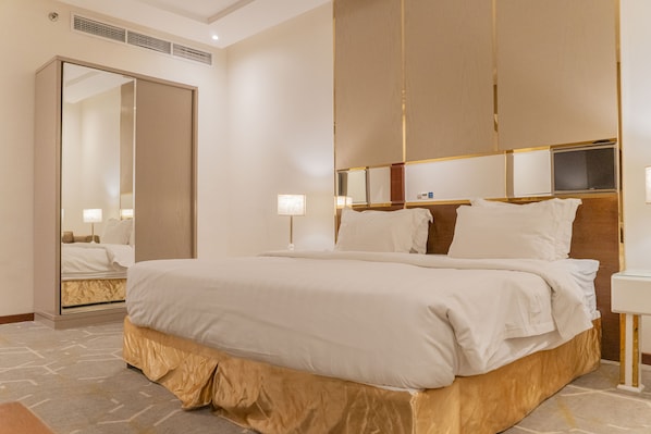 Habitación de hotel con una cama grande, un armario, una mesita de noche y un espejo.