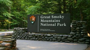 Naamplaatje voor Great Smoky Mountains National Park, met een stenen muur en beboste achtergrond.