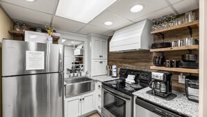 Een moderne keuken met roestvrijstalen apparatuur, witte kasten en een wand met houten accenten.