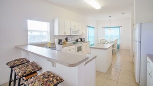 A modern kitchen with white cabinets, a microwave, and a dining area with a table and chairs. - South-Facing Private Pool • 2 Ensuites • 15 Minutes to Disney (Davenport)