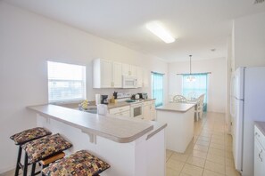 A modern kitchen with white cabinets, a microwave, and a dining area with a table and chairs. - South-Facing Private Pool • 2 Ensuites • 15 Minutes to Disney (Davenport)