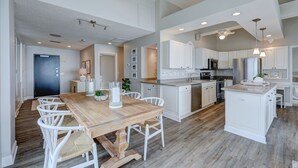 Una cocina amplia con armarios blancos, una mesa de comedor de madera y una isla central.