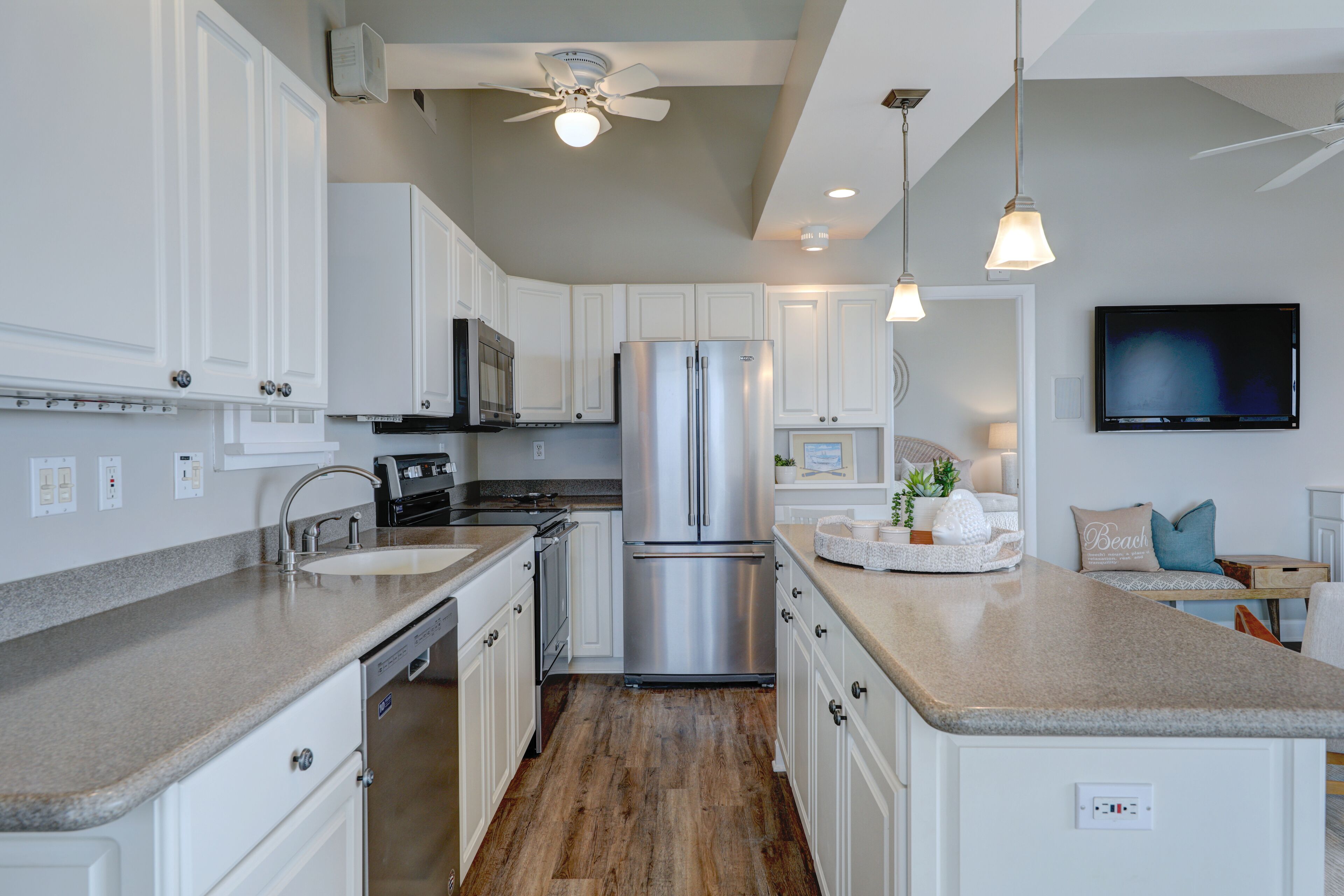 A modern kitchen with white cabinets, stainless steel appliances, and a granite countertop.