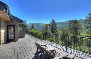 Relax on the deck with a panoramic view of the surrounding forest and mountains.
