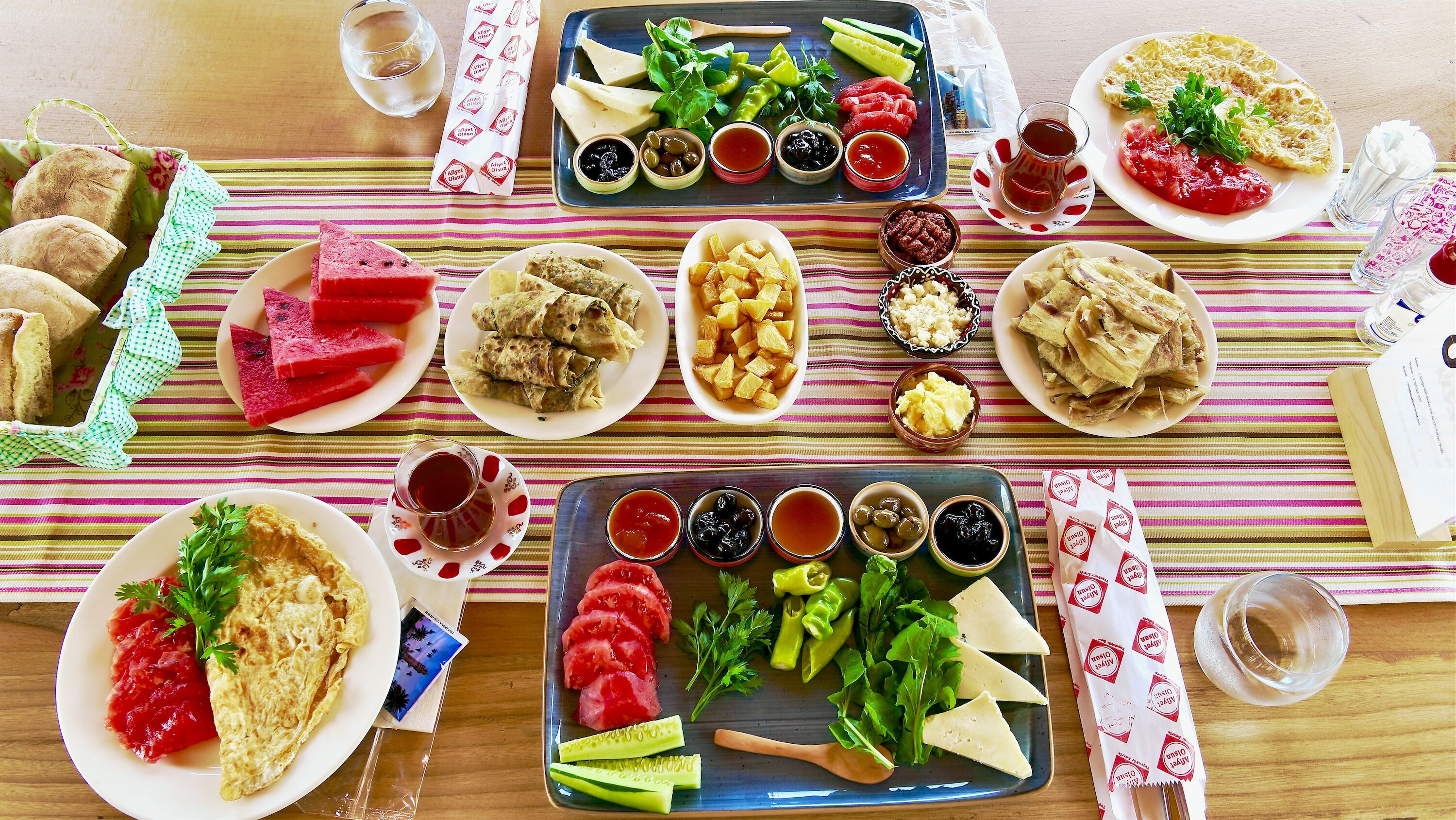Et bord dækket med forskellige retter, herunder brød, salater og saucer, der antyder et måltid.