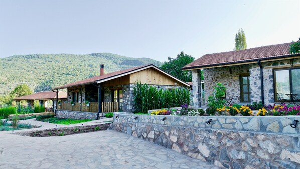 A stone building with a wooden porch and a stone wall with flower beds.