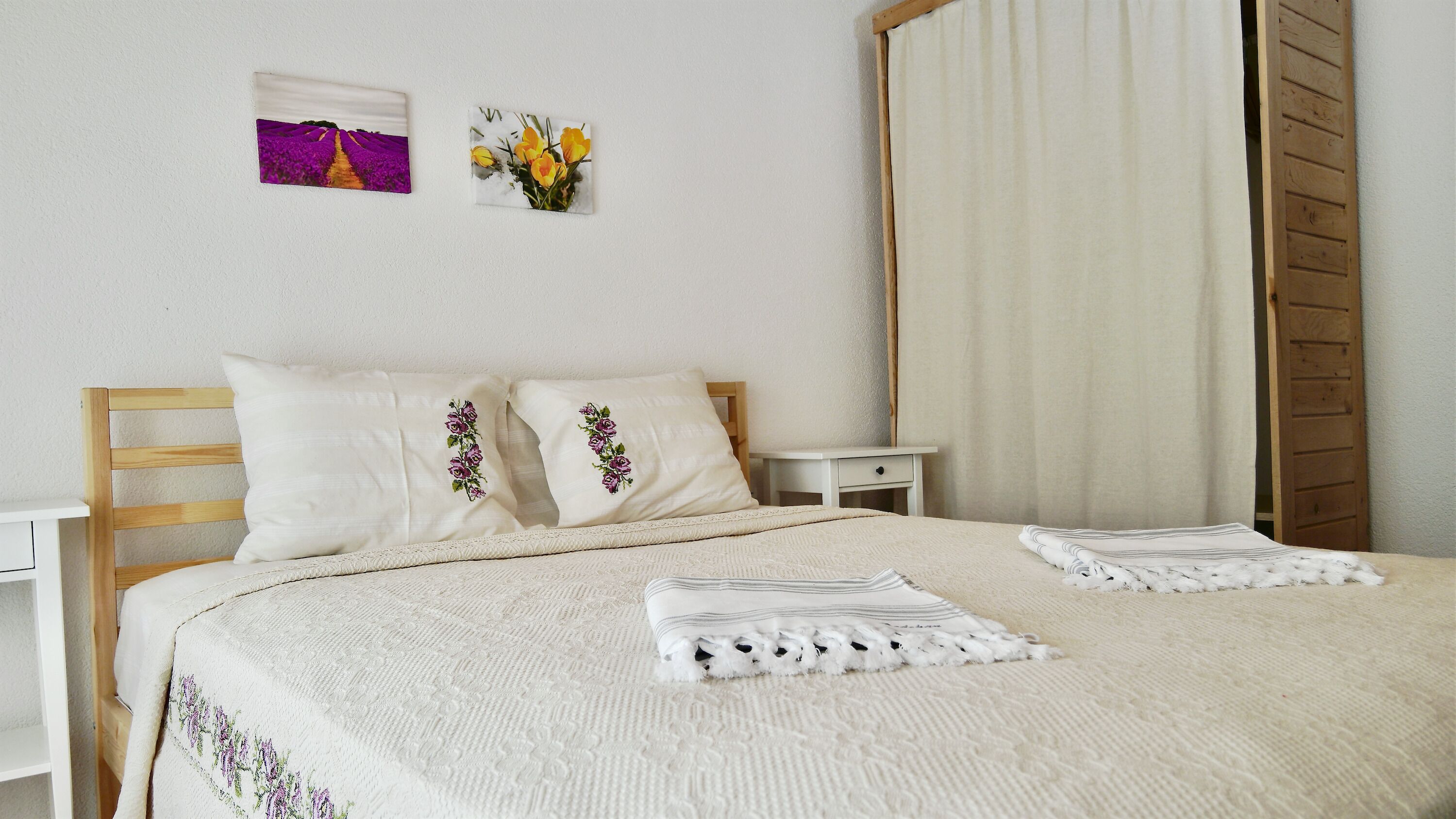 A neatly made bed with two pillows, a bedside table, and a nightstand.