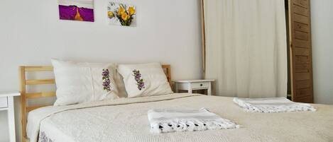 A neatly made bed with two pillows, a bedside table, and a nightstand.