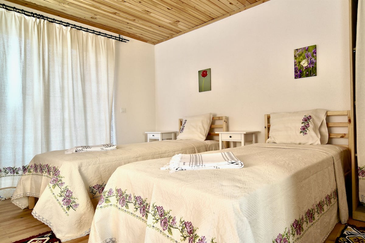A double bed room with two nightstands, a wooden headboard, and a window with curtains.