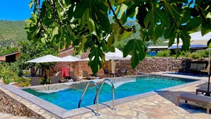 A pool area with stone flooring, lounge chairs, umbrellas, and a view of the surrounding landscape. - Dedehan Retreat Otel (Fethiye)