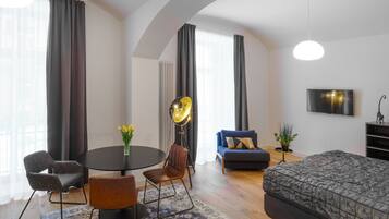 Un salon moderne avec une table ronde, deux chaises, un canapé et un téléviseur.