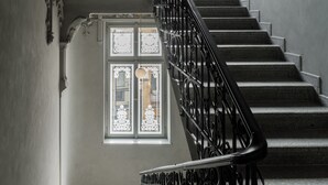 Una gran escala amb barana ornamentada i un sostre decoratiu.