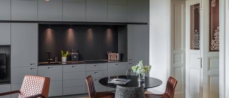 A modern kitchen with dark cabinetry, a round dining table, and a chandelier.
