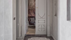 Un passadís amb un sostre decoratiu, una porta amb detalls ornamentals i una cadira al fons.