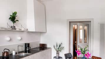 Una cocina moderna con una isla central, una zona de comedor con una mesa redonda y sillas, y una lámpara en el techo.