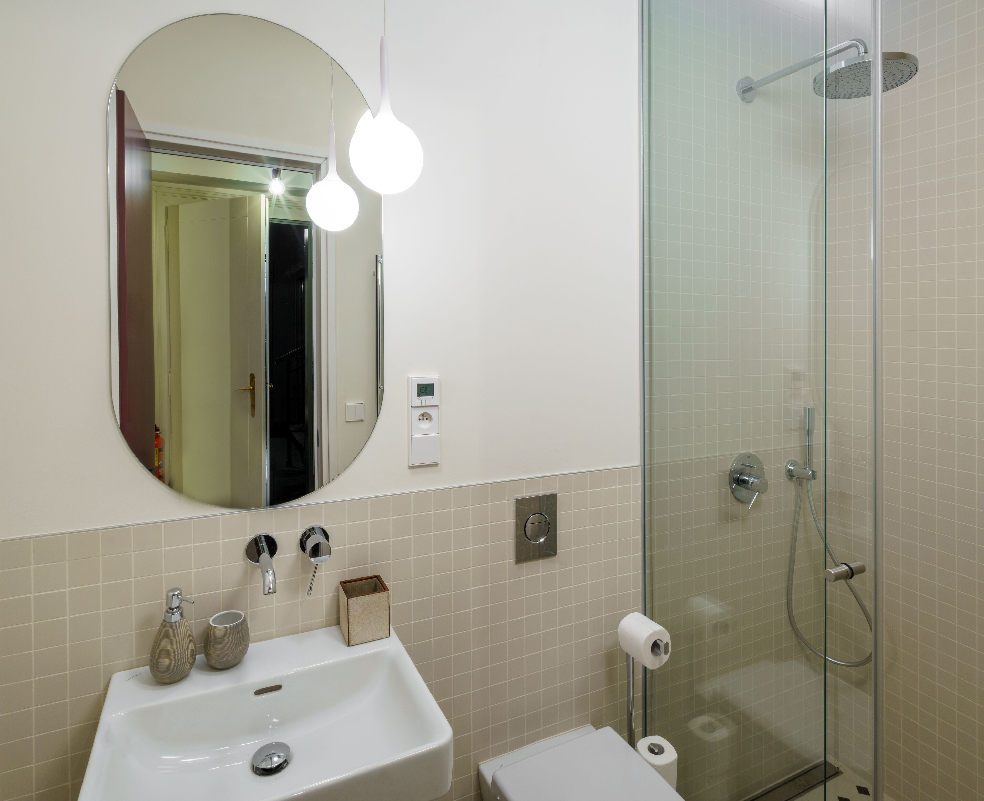 A bathroom with a sink, mirror, and shower.