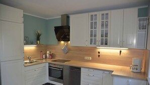 Een moderne keuken met witte kasten, een roestvrijstalen oven, een vaatwasser en een koffiezetapparaat.