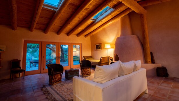 A cozy room with a wooden ceiling, a white sofa, and a large window overlooking a garden. - Peaceful family/group home with private attached treehouse (Canones)